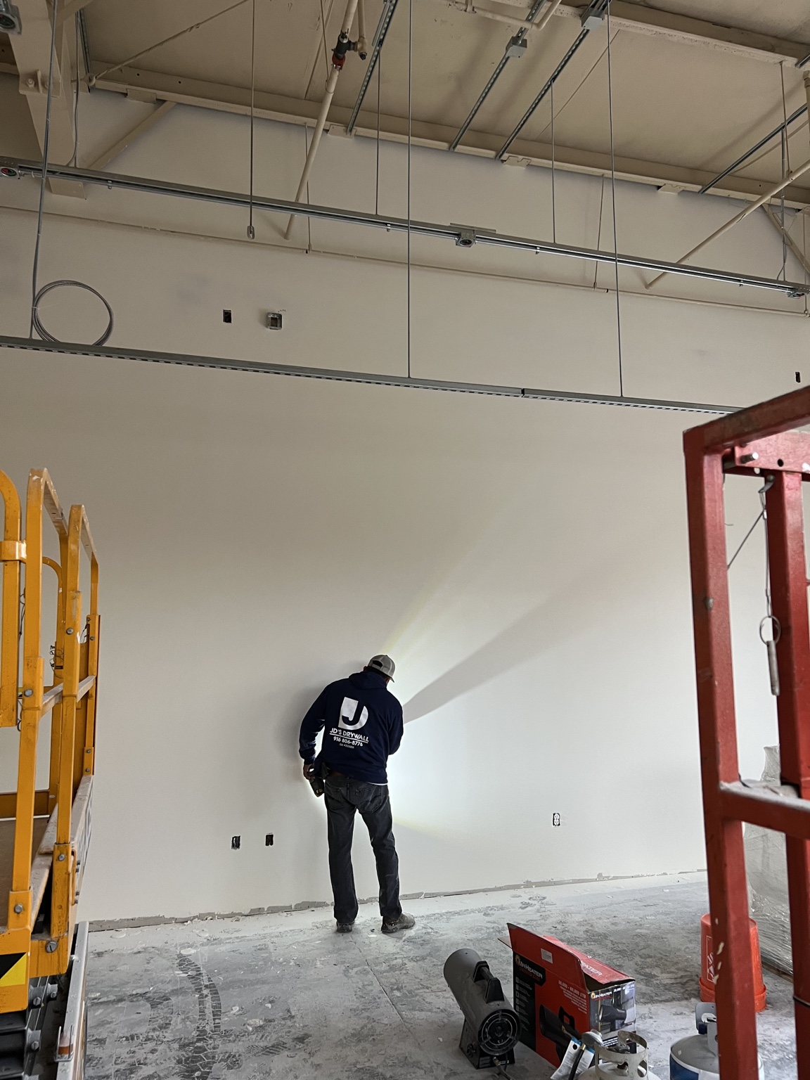 JD’s Drywall craftsman inspecting a large finished wall